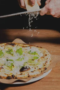 Cheese being grated on a lemon pizza at Luminosa