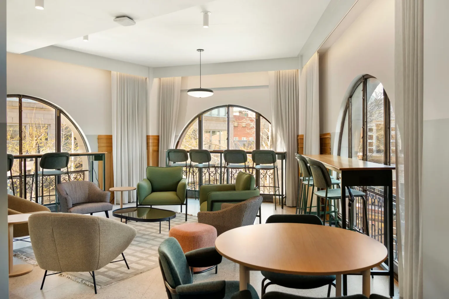 chairs arranged throughout the pointed apex of the iron works lounge, with bay windows on all three sides