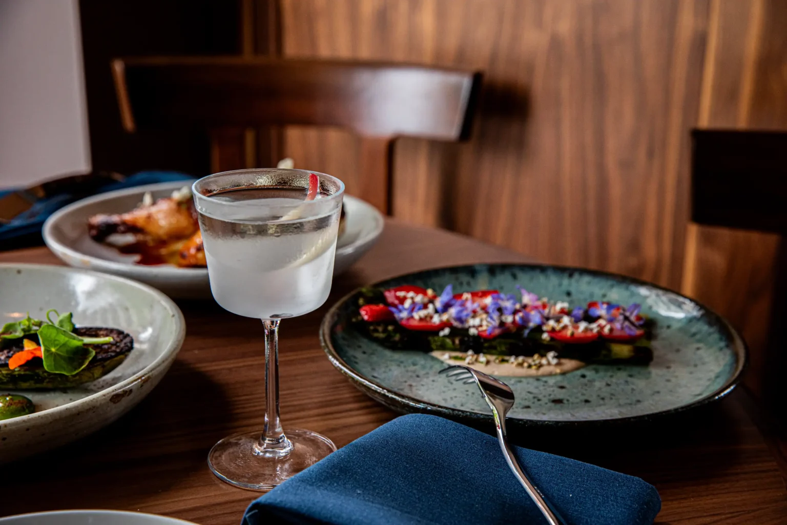 a locally inspired cocktail next to entrees from Luminosa