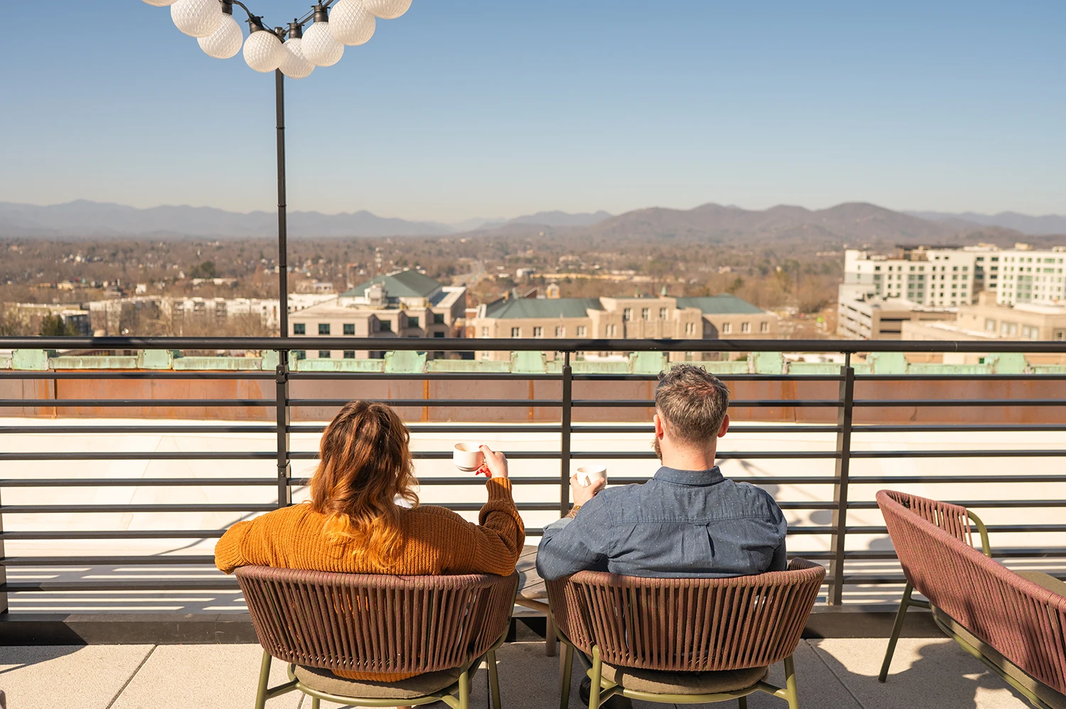 a couple enjoying the view and a cup of coffee at the rooftop caffe at the flat iron hotel