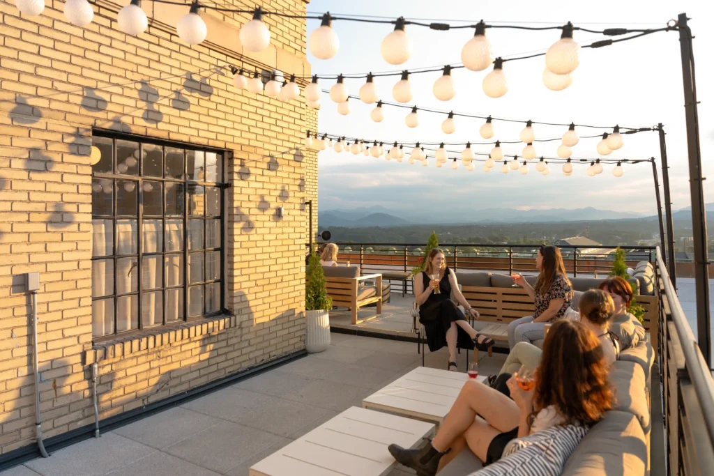 people having drinks at sunset on the rooftop bar at the flat iron hotel