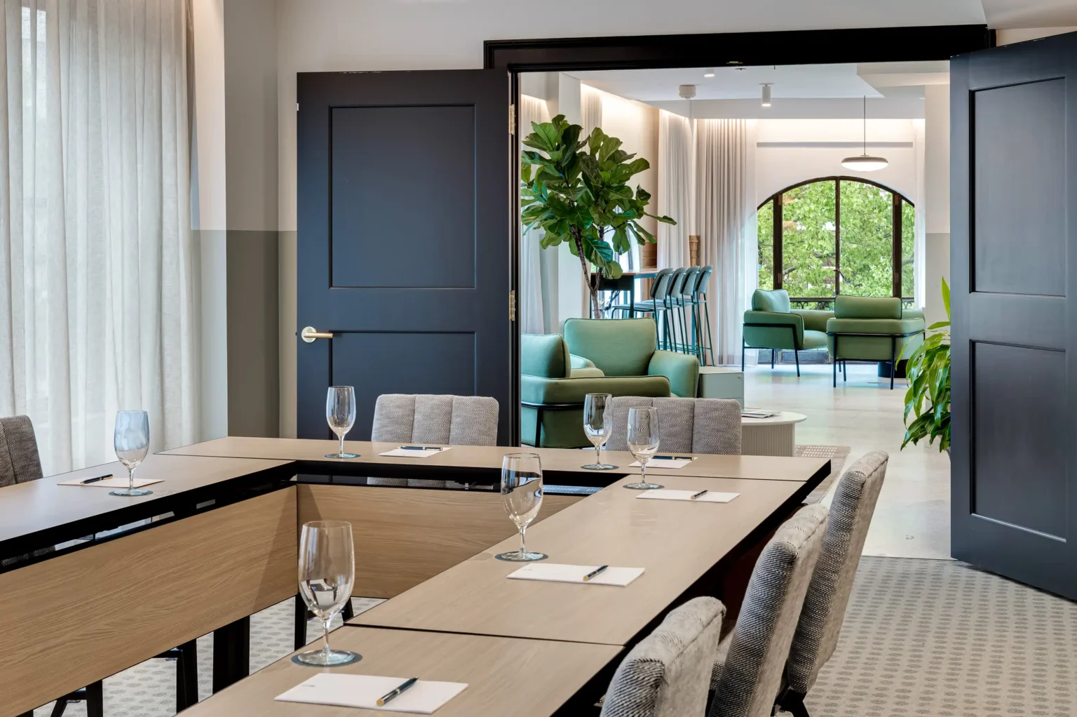 a conference room that opens up into a larger sunlit meeting space