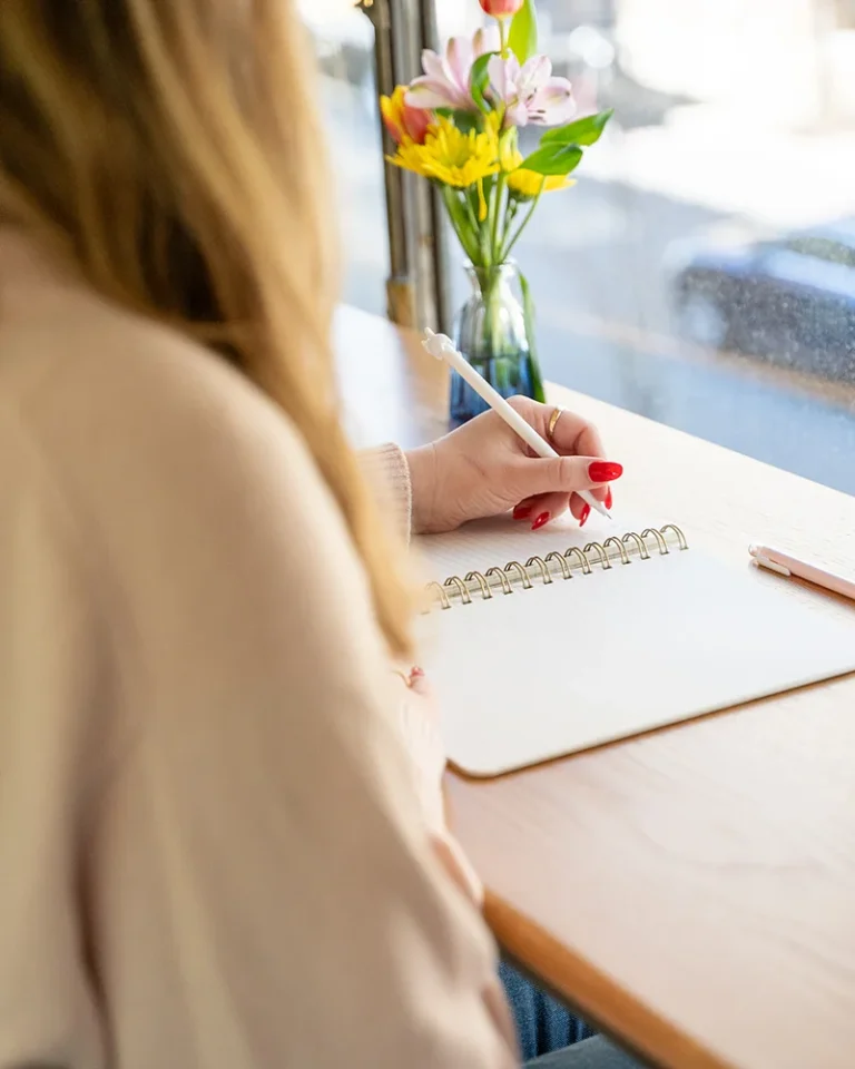 a woman writes in a window seat