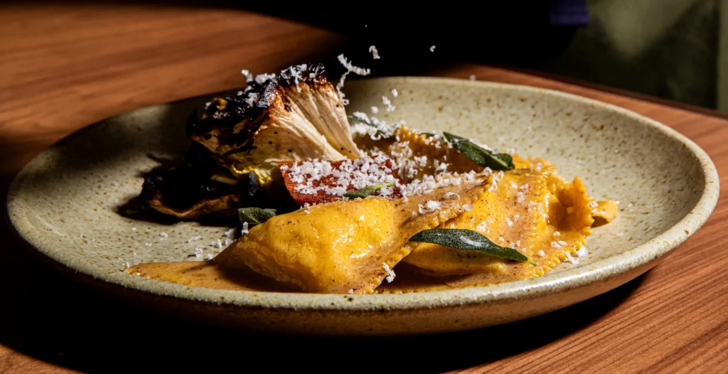 a triangolini dish with charred vegetables and freshly shredded cheese from luminosa