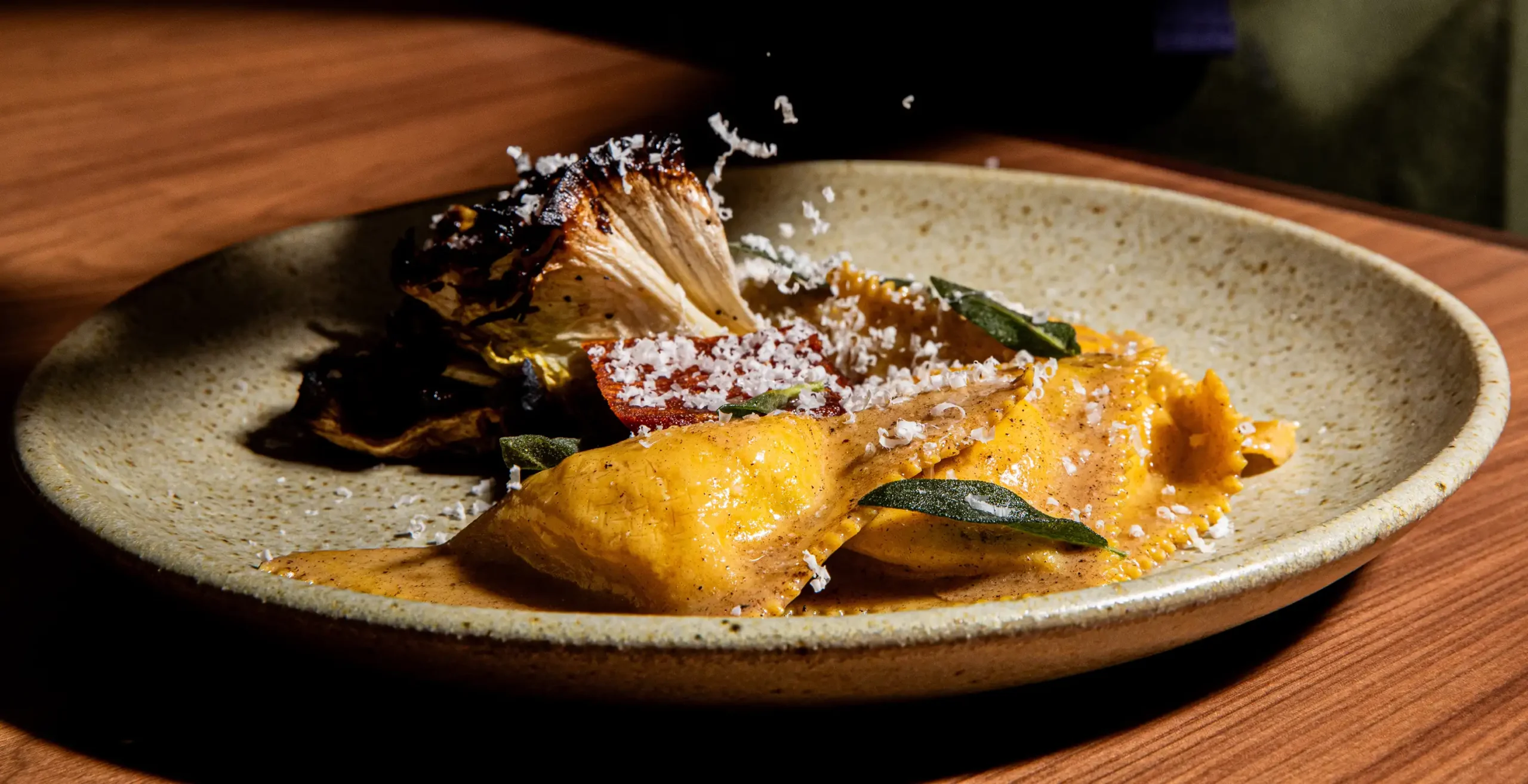 a triangolini dish with charred vegetables and freshly shredded cheese from luminosa