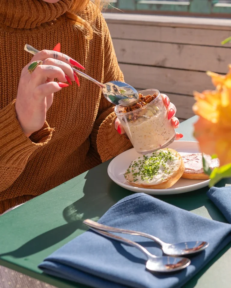 a woman eats a parfait on a rooftop