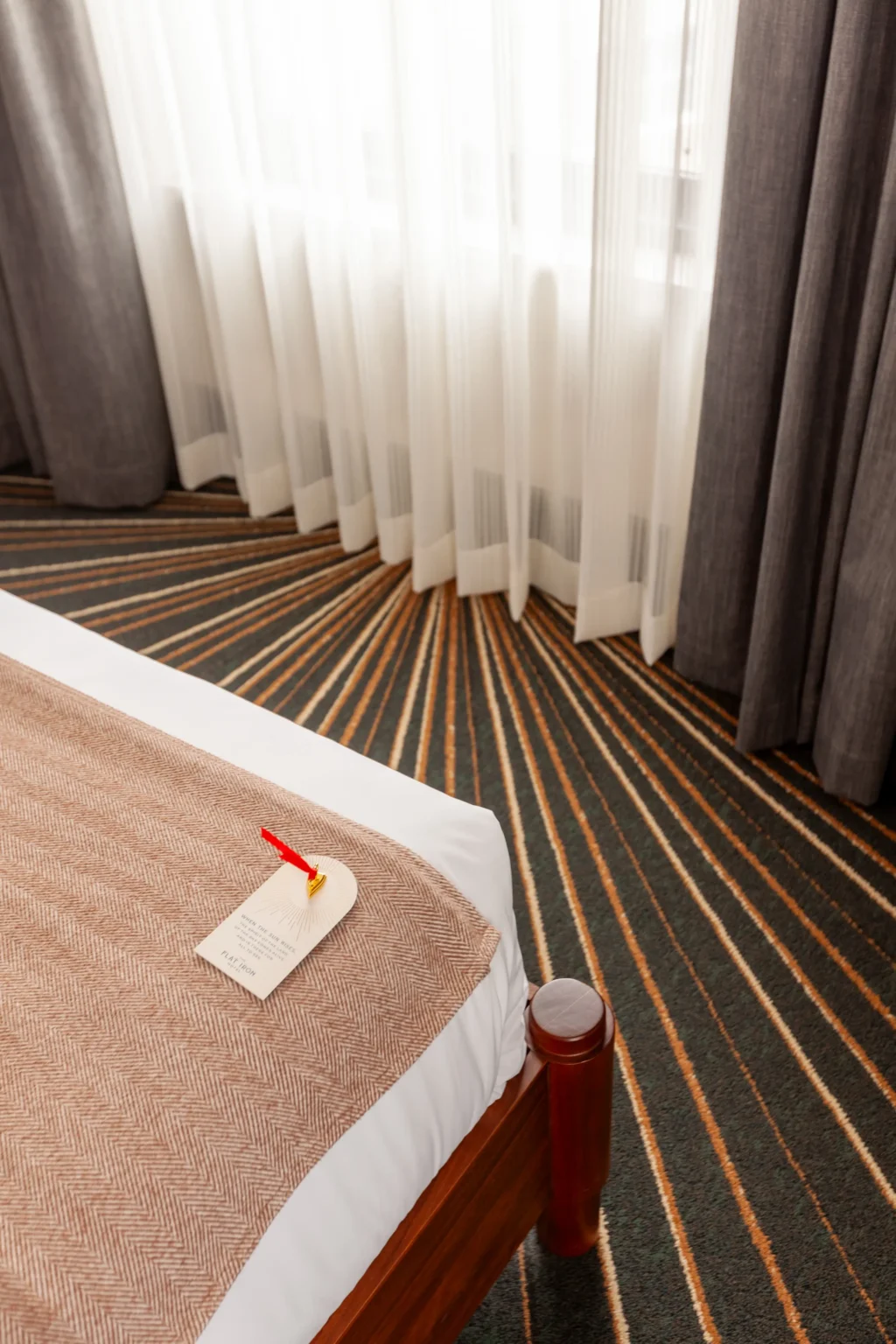 detail of the bed in the Apex King suite, with a gold iron token waiting on the sheets