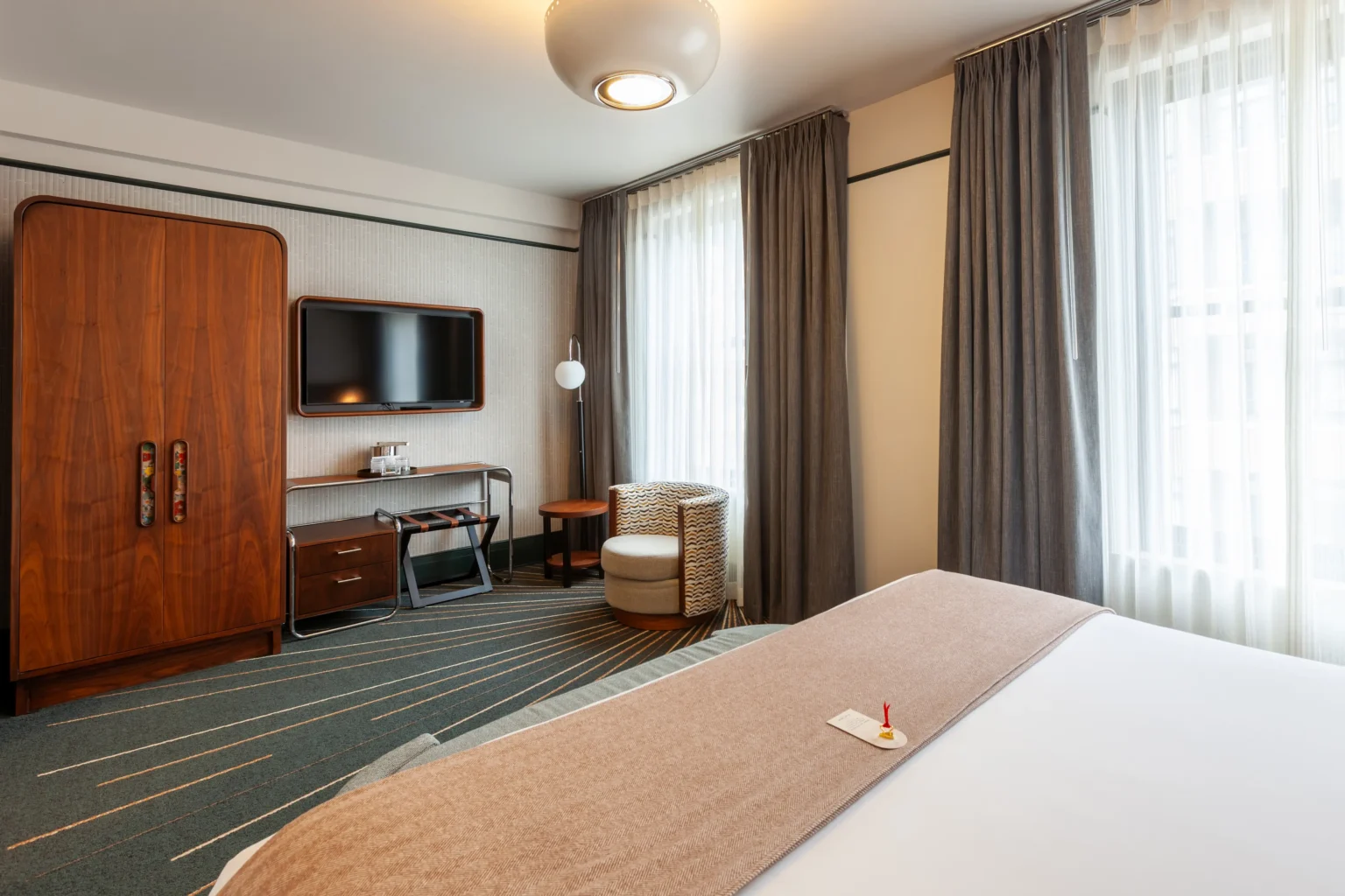 king room, with armoire, tv and sitting area, and part of the bed