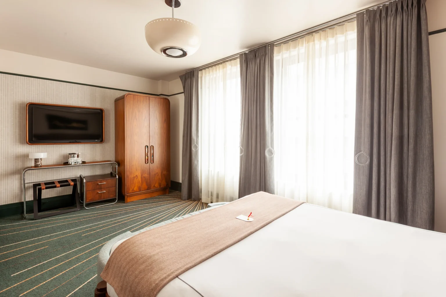 Premier King Suite at the flat iron hotel , showing the tv , table, armoire and part of the bed