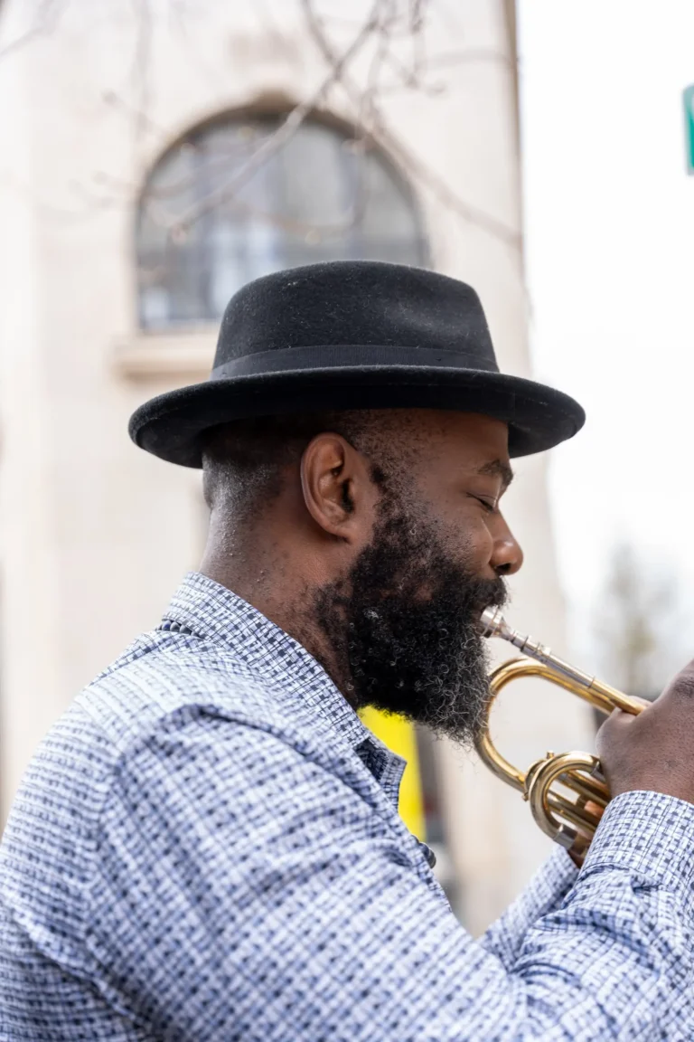 a busker plays the trumpet by the Flat Iron Hotel