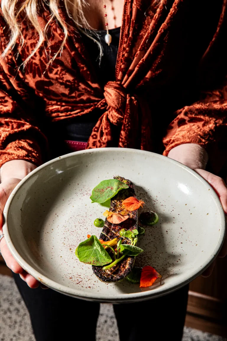 A grilled eggplant with floral garnish