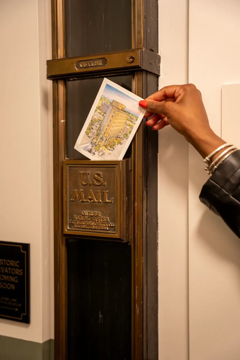 A woman drops a postcard down the chute at the Flat Iron Hotel