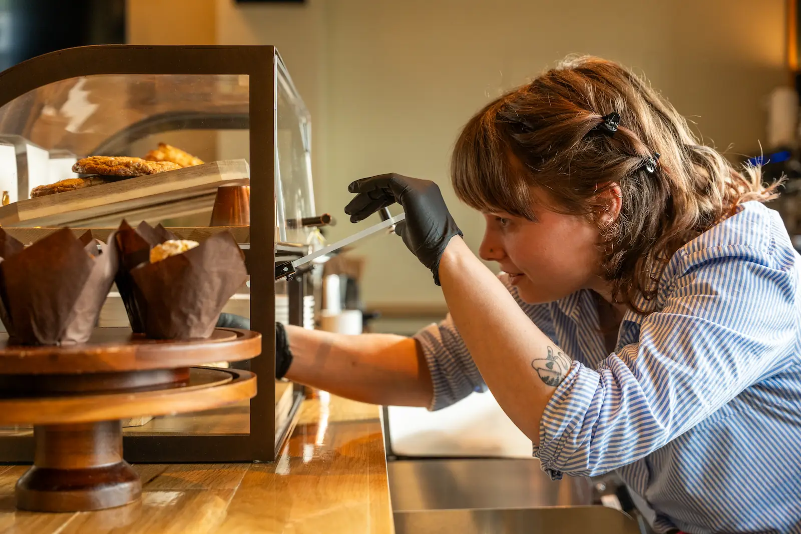 a barista selects pastries from a display case
