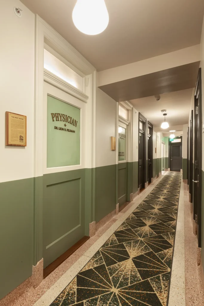 a guest hallway in the Flat Iron Hotel, with doors featuring antique signage and historical plaques