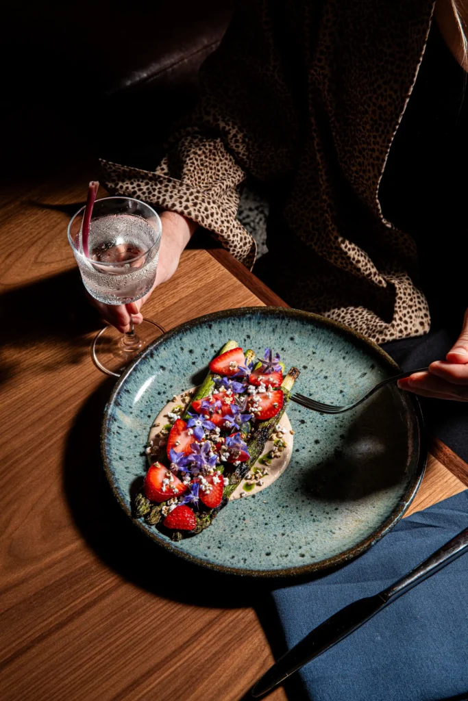 a woman enjoys creatively plated and wood-fired veggies during a private dinner at Luminosa